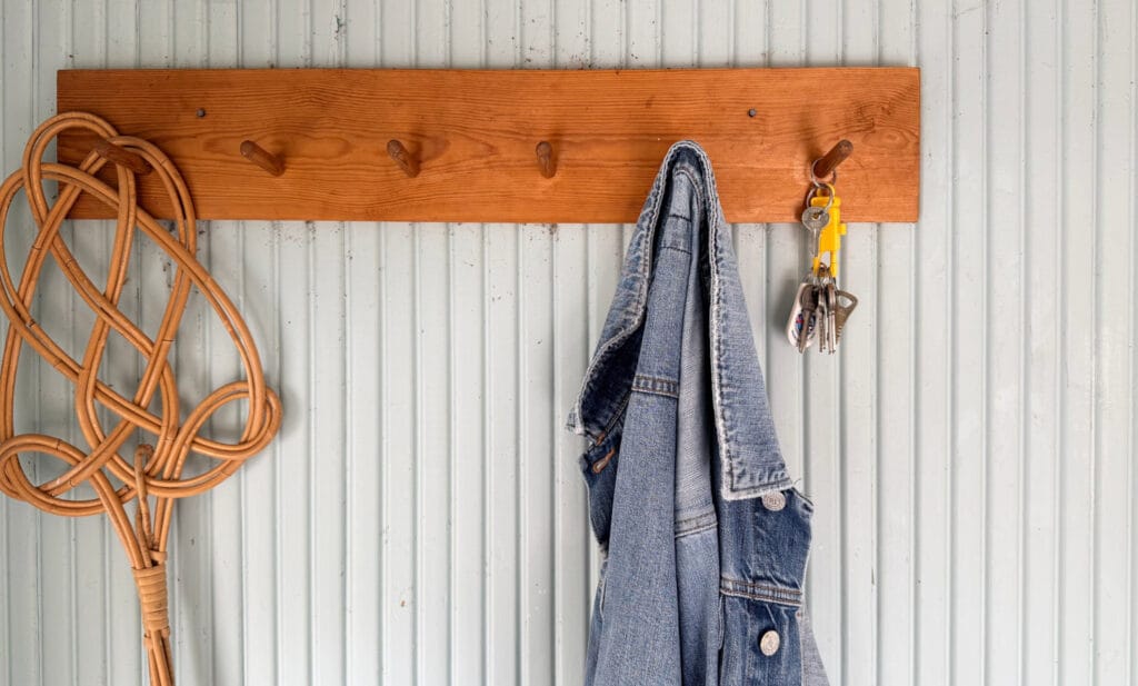 Naulakk, jossa roikkuvat mattopiiska, avaimet ja farkkutakki.