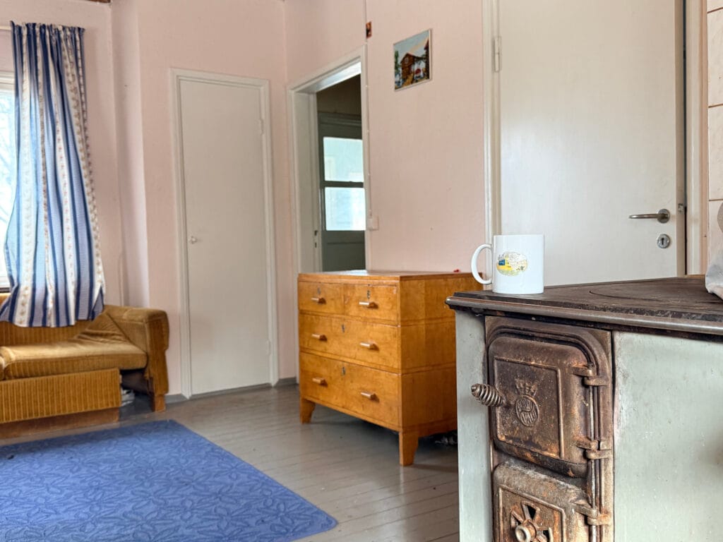 Huone, jonka etualalla leivinuuni. Takana lipasto, lattialla sininen matto.