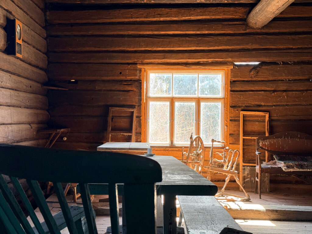 Hämärä hirsitupa, jonka perällä ruutuikkuna.