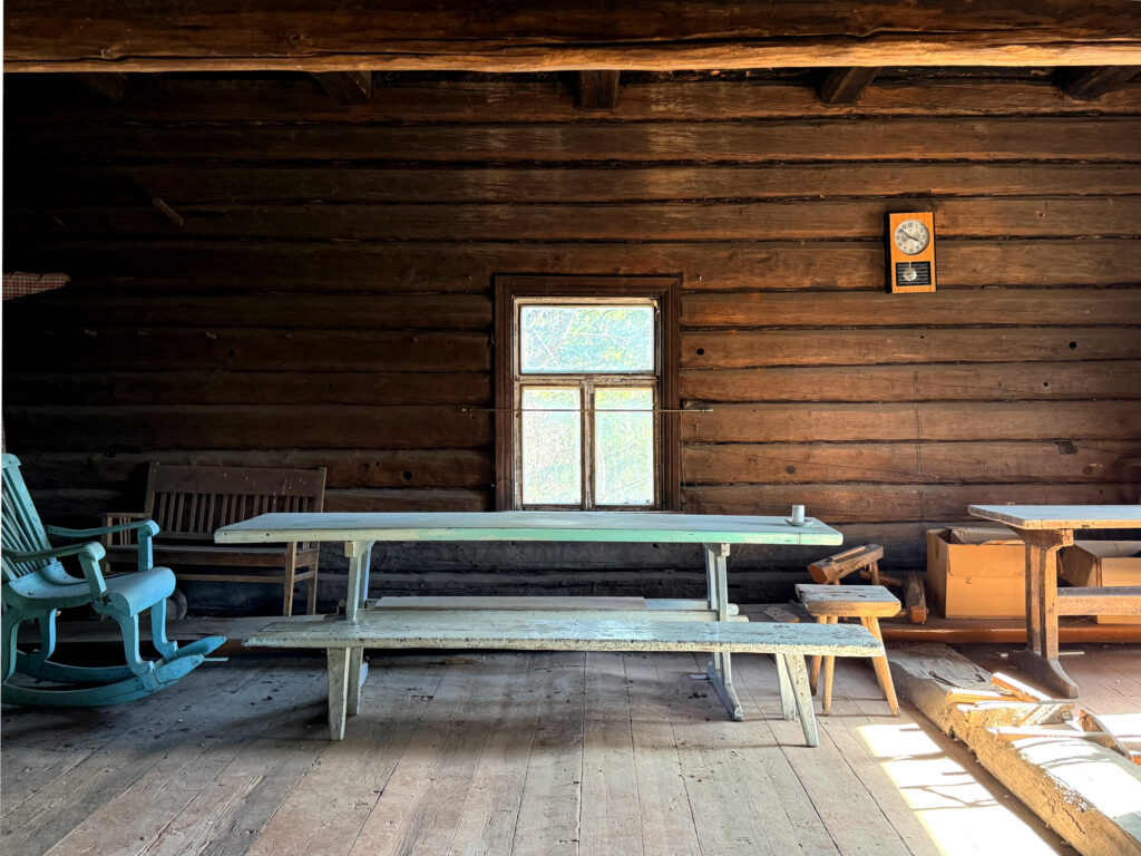 Hirsiseinän edessä turkoosi pirttiryhmä, jonka päässä keinutuoli.