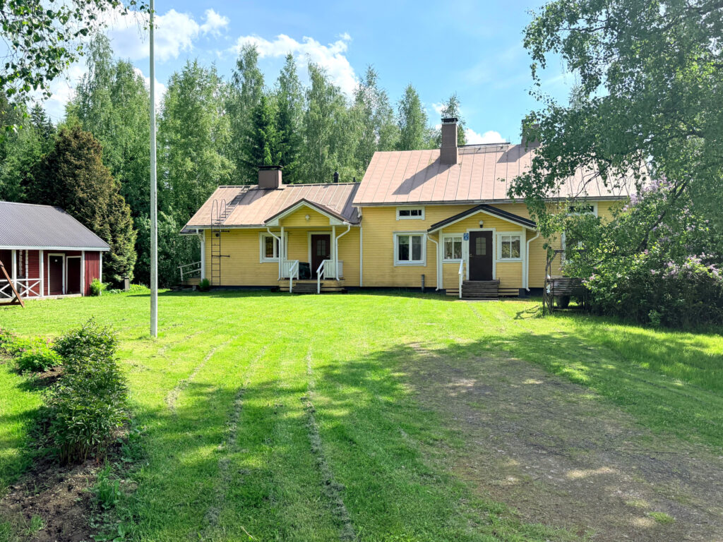 Keltainen talo vihreän nurmen takana.
