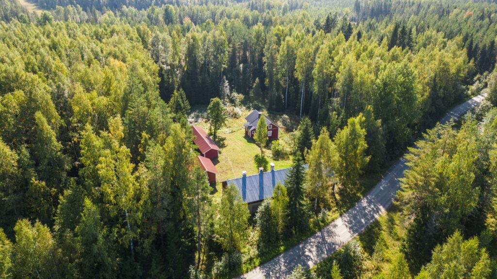 Ilmakuva, punainen talo metsän keskellä.