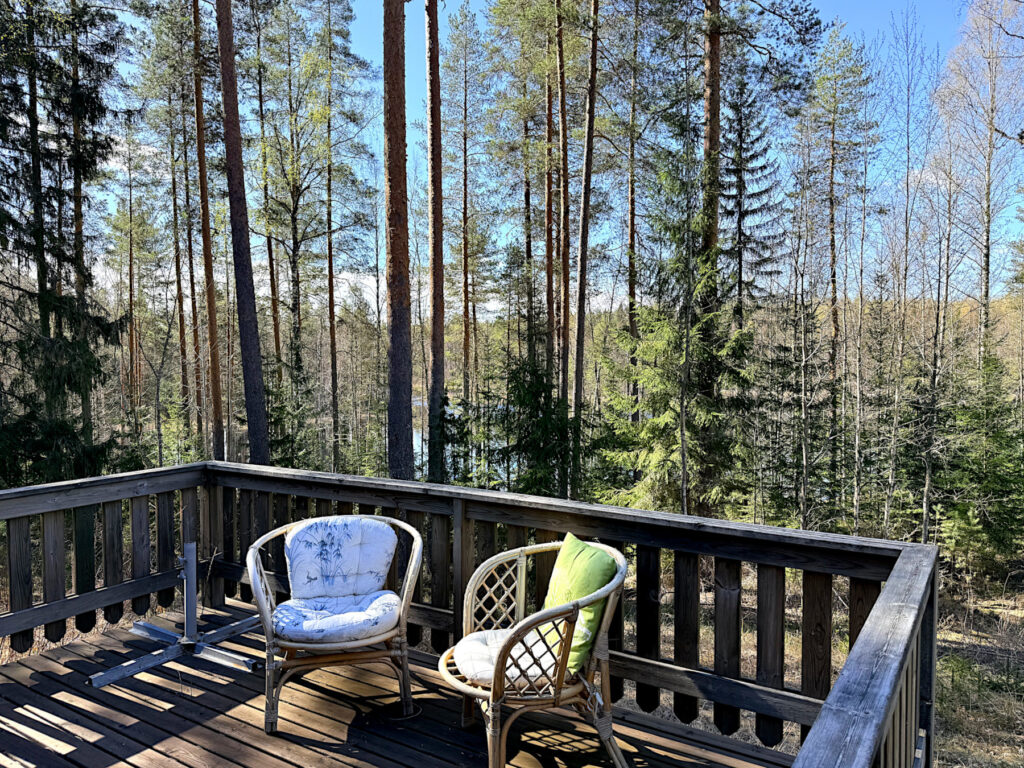Terassi, jolla kaksi tuolia. Takana mäntymetsä.