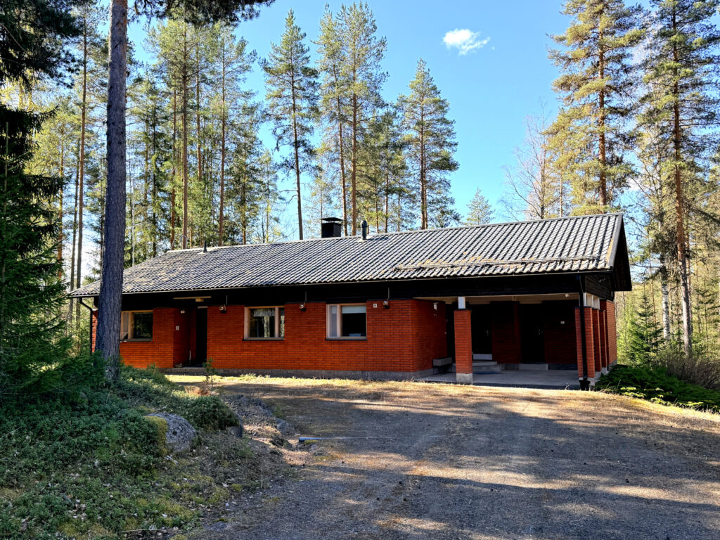 Punatiilitalo metsäisessä maisemassa.
