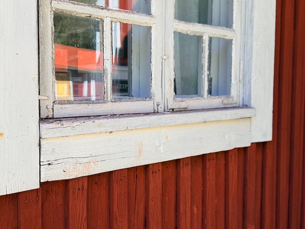 Lähikuva talon ikkunalaudasta ja ikkunan ristikoista.