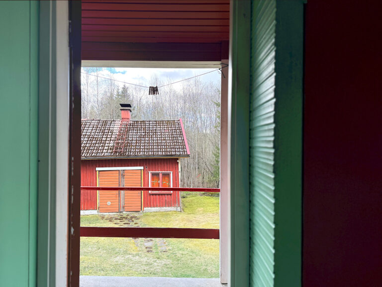 Näkymä ovelta ulos, jossa punainen piharakennus.