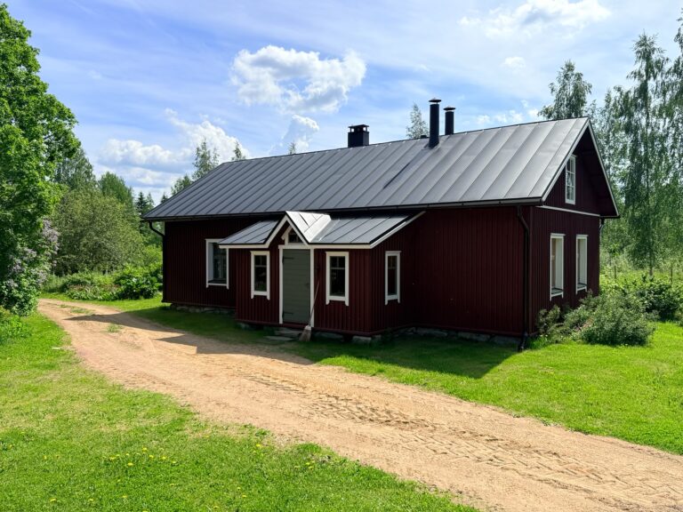 Punainen talo. Vihreä nurmi ja sininen taivas.